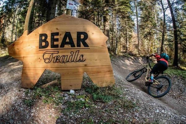 Insegna Bear Trails accanto a un biker nel bosco
