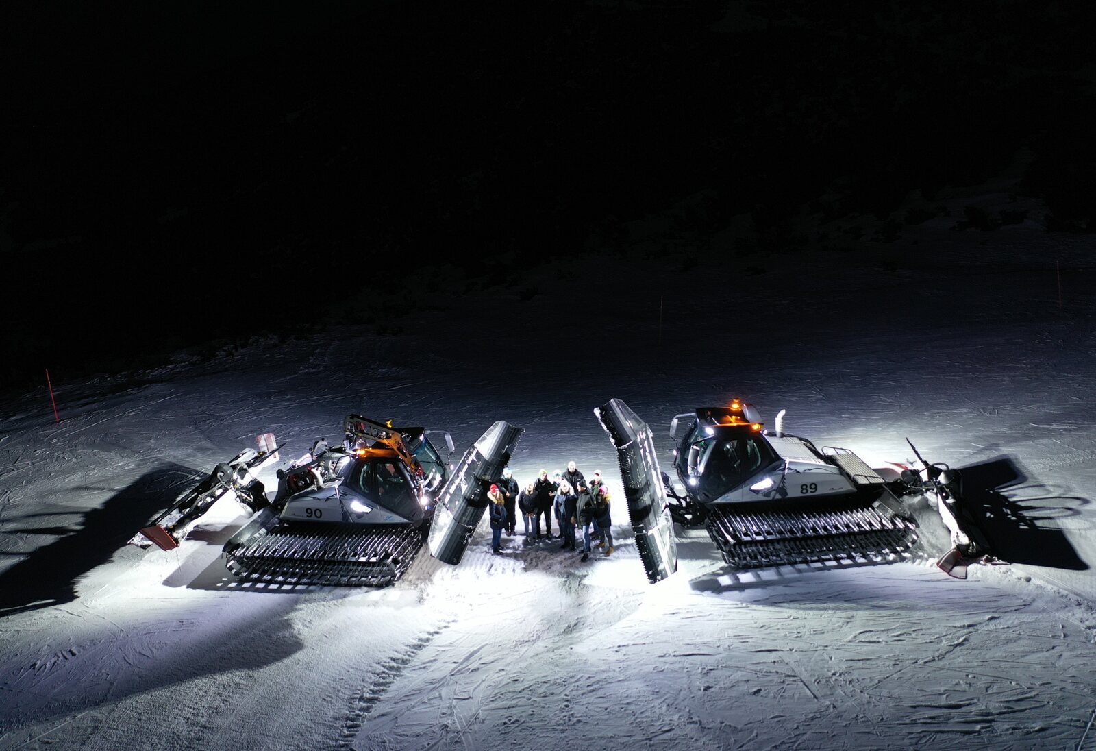 Gatti delle nevi con persone durante la preparazione notturna delle piste