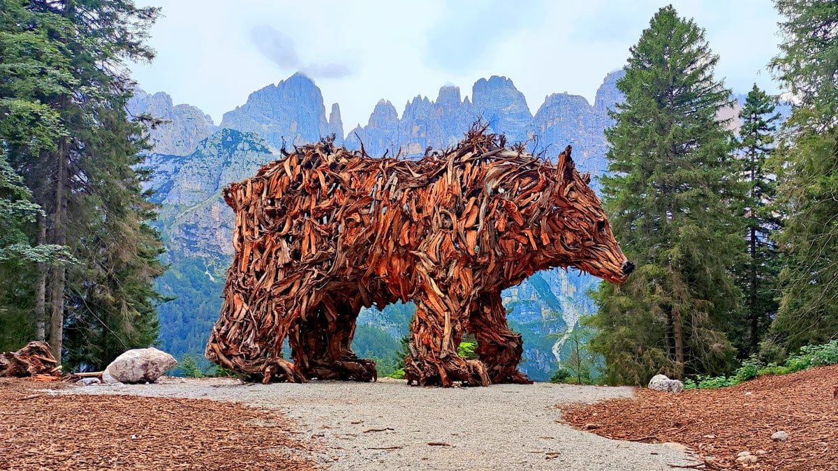 Scultura lignea dell’Orso del Pradel di Marco Martalar davanti alle Dolomiti di Brenta